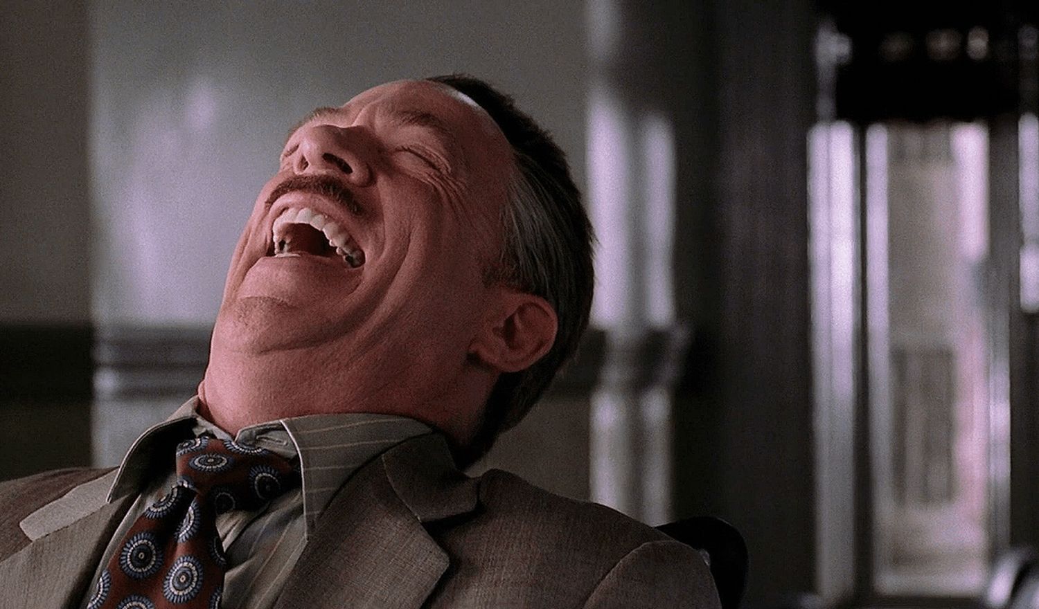 A man laughing with his eyes closed.